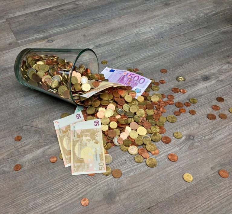 coins and bills in a glass toppled over