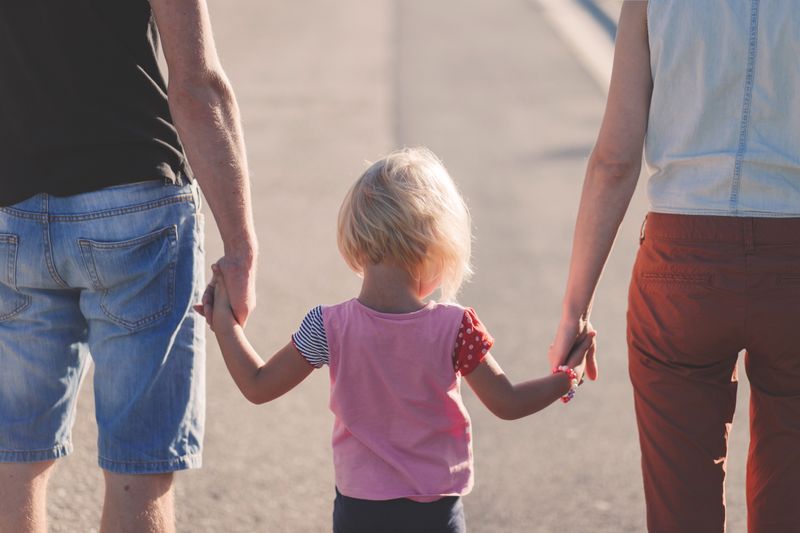 a couple holding their child's hands